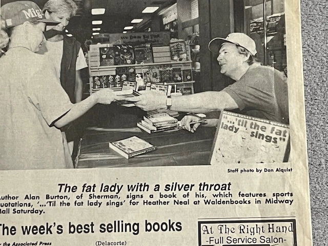 newspaper article with a photo of Alan signing a book at a table