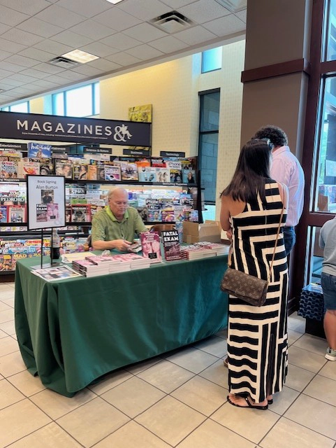 Alan Burton at a table signing books for visitors